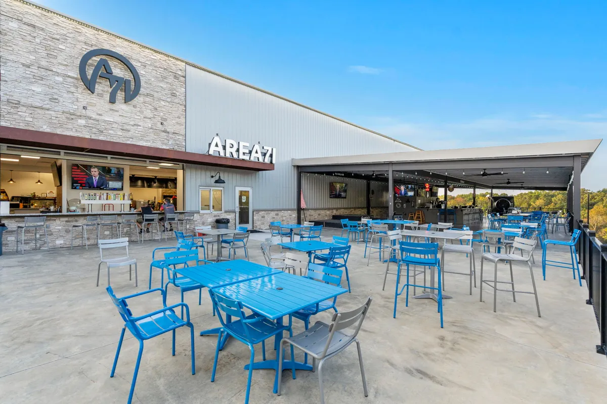 An inviting exterior seating area with prominent signage for AREA 71, a lively bar area with patrons, and an open-air vibe. The space is designed for social gatherings, casual dining, and watching sports or live entertainment, reflecting the property's proximity to local attractions.