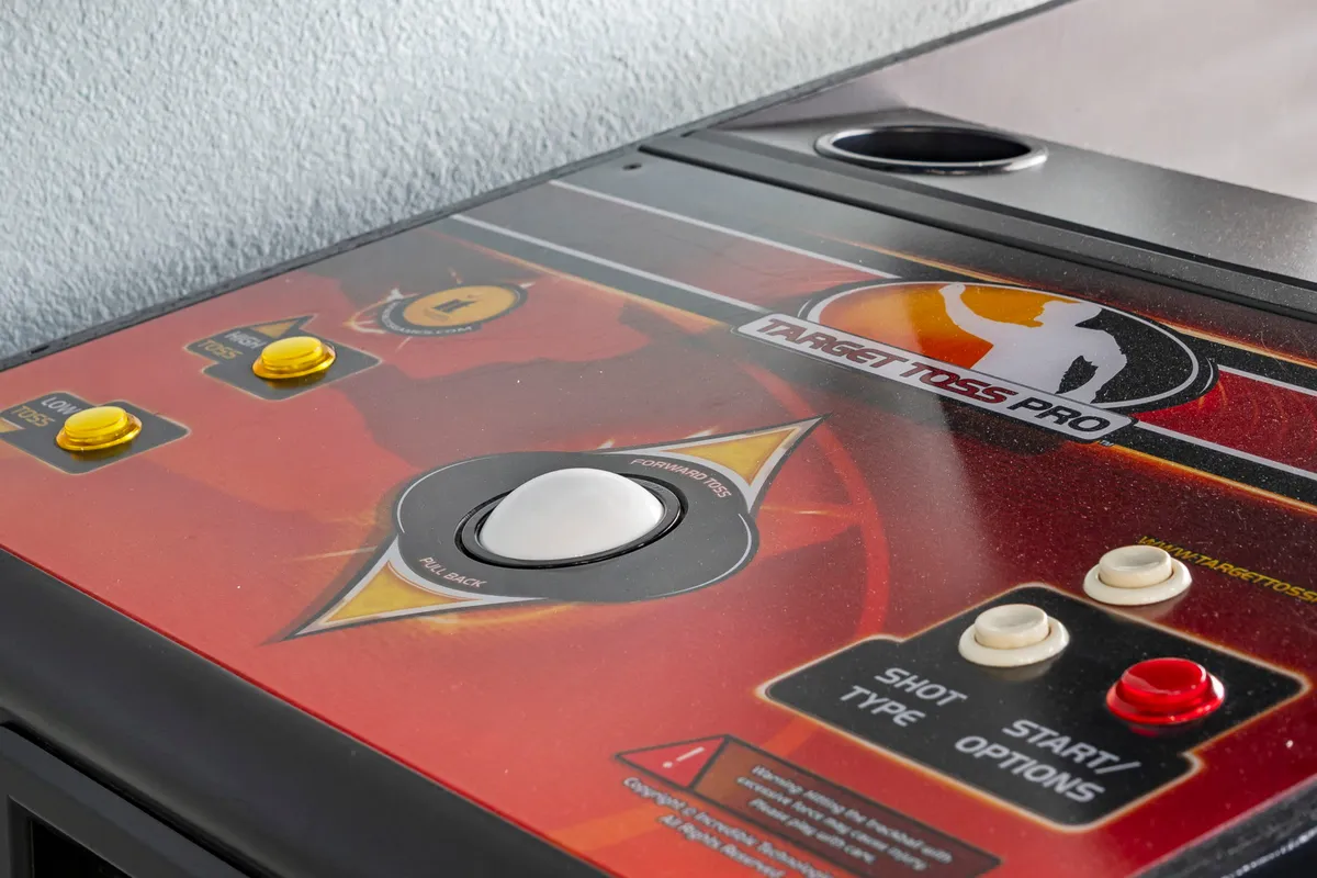 A close-up of brightly colored arcade game controls and game surfaces, evoking excitement and playful competition. The vibrant details highlight the interactive gaming experience available to guests.
