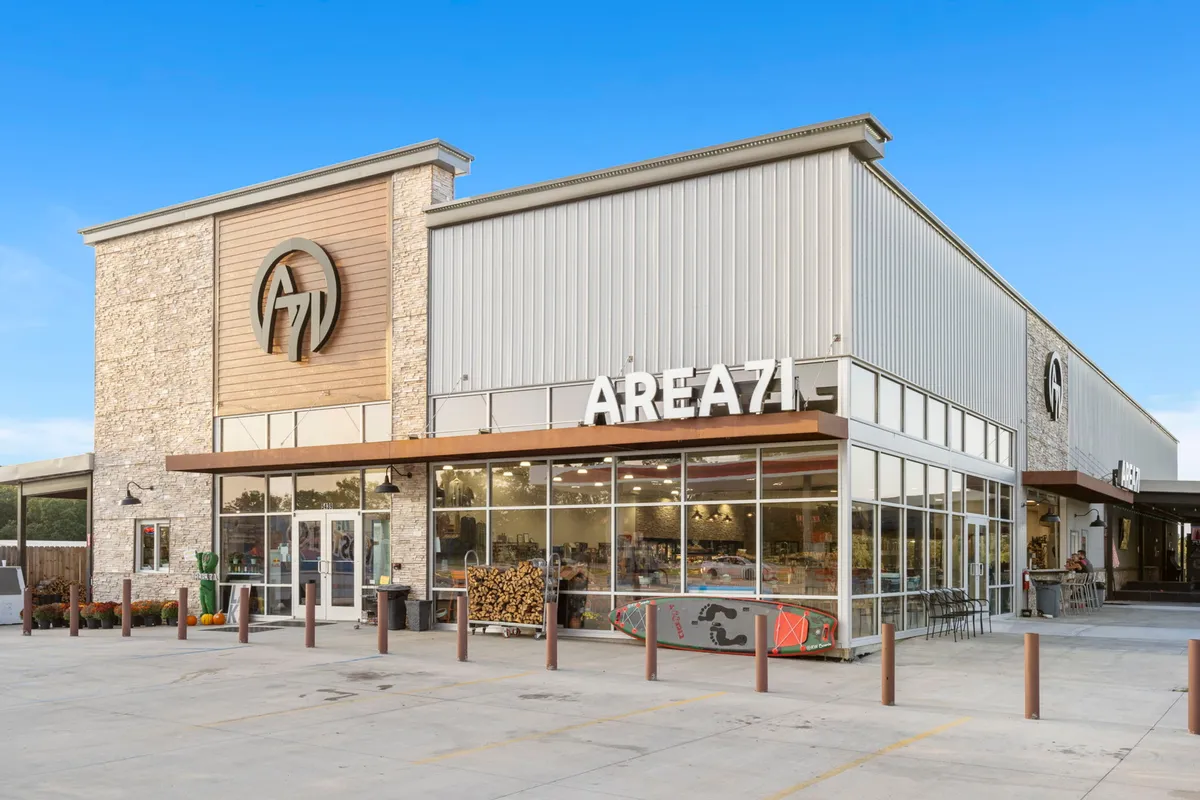 The image shows the prominent exterior of Area 71, featuring a large 'AREA71' sign, a stylish glass facade, and decorative wooden elements. The entrance is inviting and signals a lively, welcoming atmosphere, perfect for social gatherings.