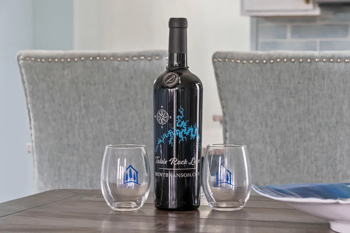 A wooden table set with a wine bottle and glasses, inviting guests to toast special moments and enjoy each other’s company in a relaxed atmosphere.