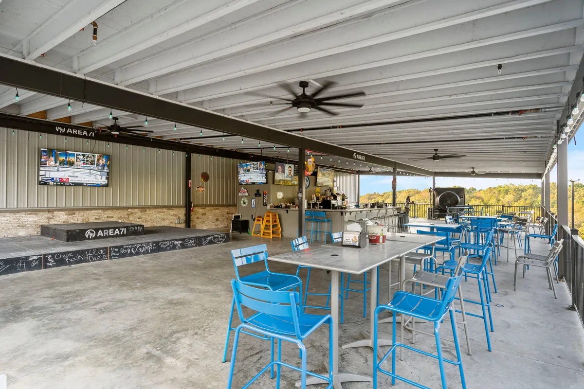 The exterior patio and bar area at Area 71, with ample seating, large screens for televised sports, an open and lively atmosphere, and a stage area for live performances. Guests can be seen enjoying social activities, highlighting the communal, energetic vibe.