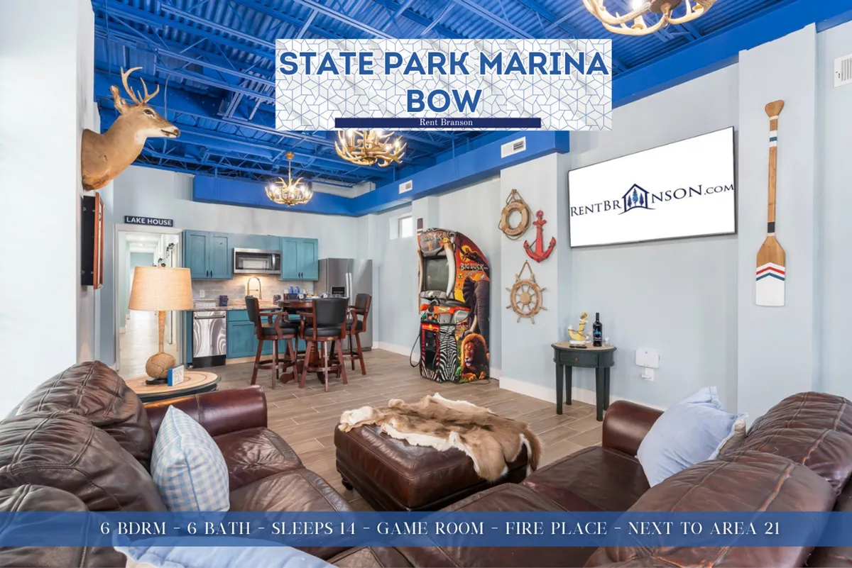 A spacious game room area featuring a decorative deer head, arcade machine, dining table, and cozy furnishings. The fireplace adds a touch of warmth, making the space ideal for both competitive play and relaxation.